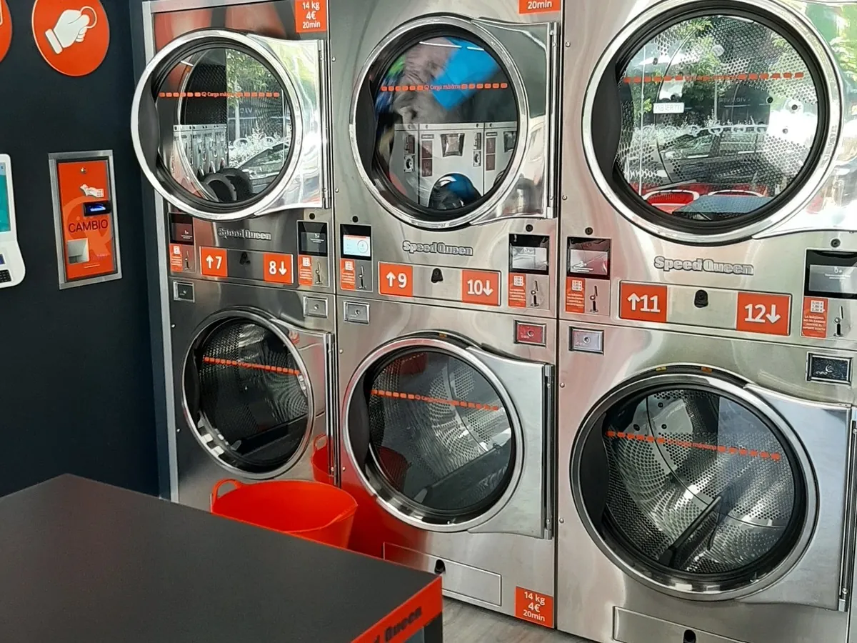 Sèche-linge professionnels Speed Queen avec les tarifs affichés dans une laverie Gira Gira